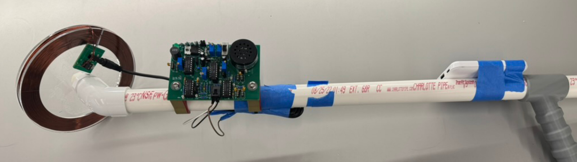 The finished metal detector: a hand-wound copper coil with the custom PCB and speaker mounted to the shaft.